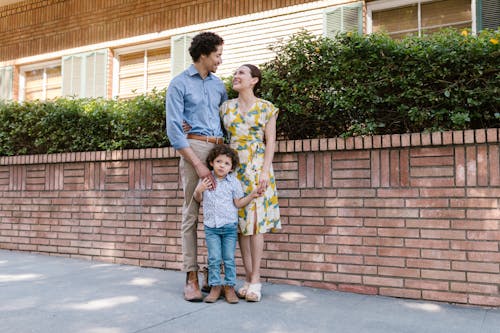 A Family Standing Beside the Brick Wall