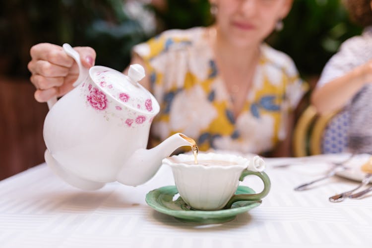 Woman Pouring Tea On A Cup