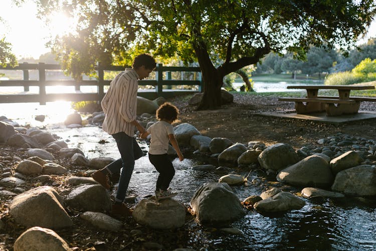 Father And Child Walking On The Rocky River