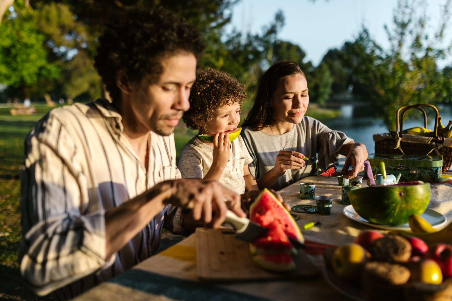 減重遇家庭飲食衝突?實用解法平衡個人與家人 A cheerful family sharing a delightful picnic outdoors, enjoying watermelon on a sunny day.