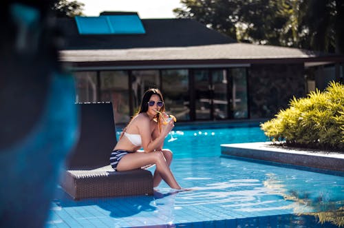 Selective Focus Photography of Woman Wearing Black and White Bikini Sitting Brown Chair