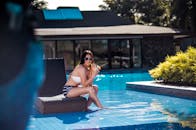 穿着泳衣的女人在游泳池边喝着饮料，感受着夏日的氛围