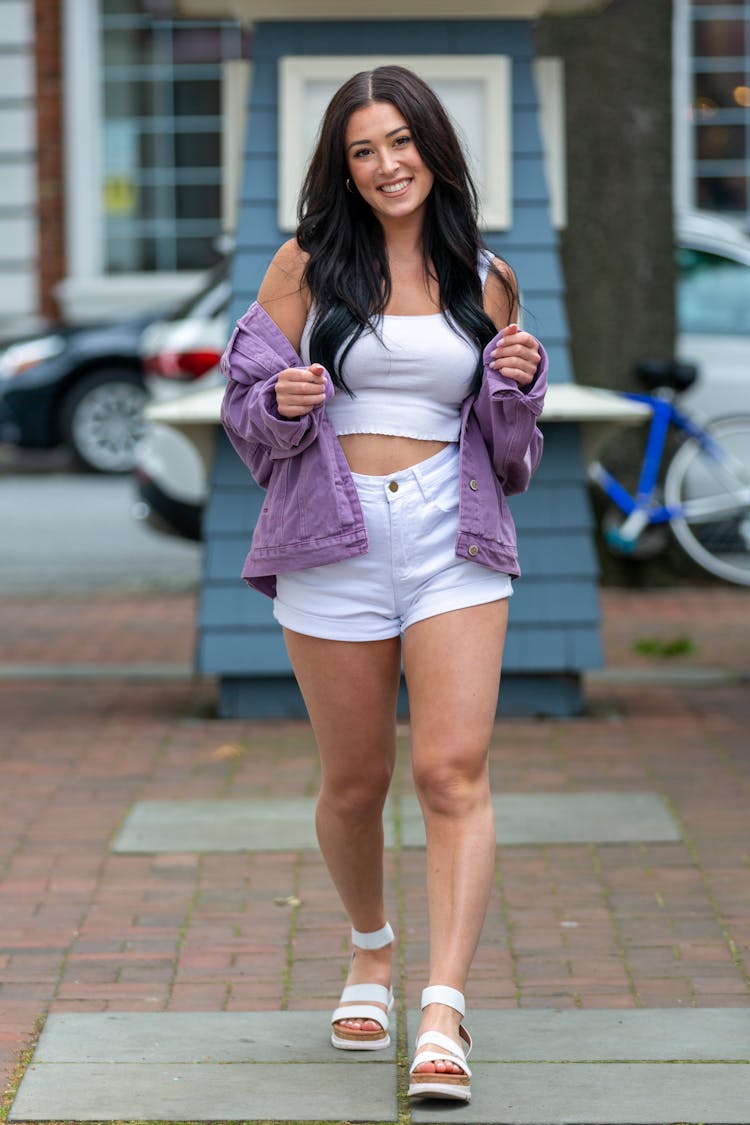 A Woman In White Crop Top And Shorts Walking On The Pavement