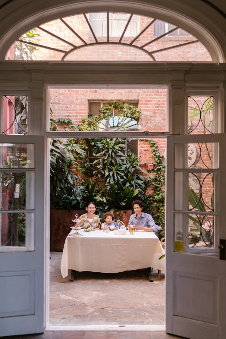 Family With A Little Son Sitting At The Table In A Restaurant Patio 