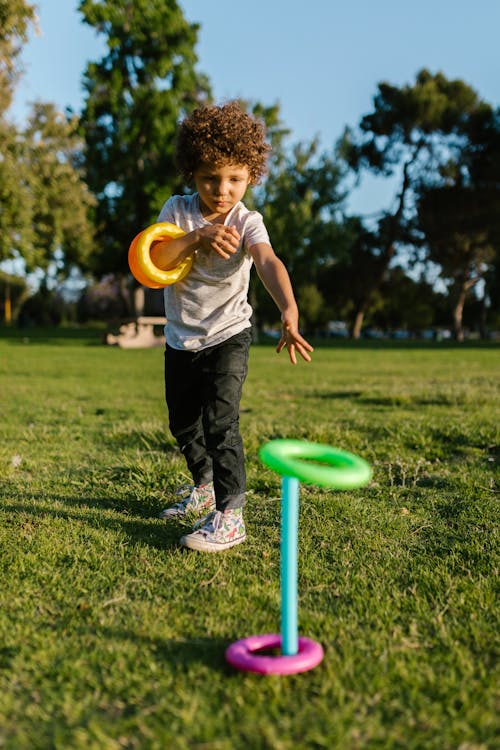 A Boy Playing Colorful Ring Toys in the Park