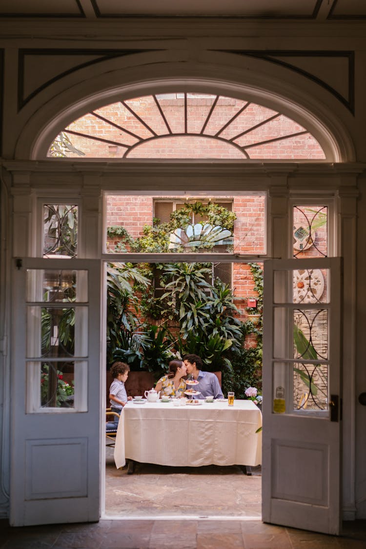 Family With A Little Son Sitting At The Table In A Restaurant Patio 