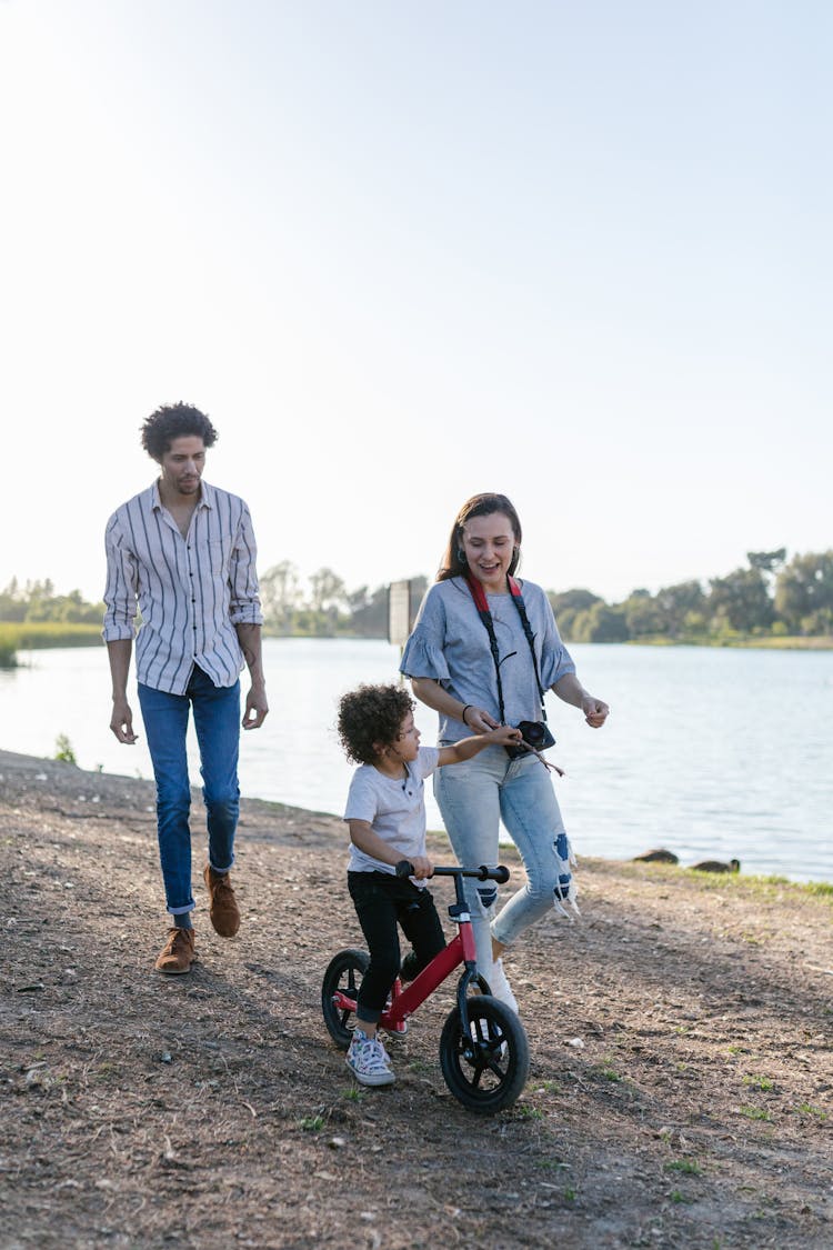 Photograph Of A Kid Riding A Balance Bike With His Parents