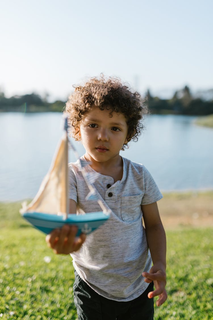 Photograph Of A Boy Holding A Toy Boat