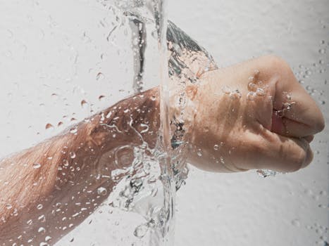 Dynamic image showing a clenched hand submerged in a splash of clear water, emphasizing motion and hygiene.