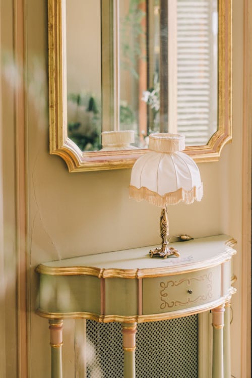 Lamp Standing on a Table under a Mirror in a Room in a Vintage, Luxurious Style 