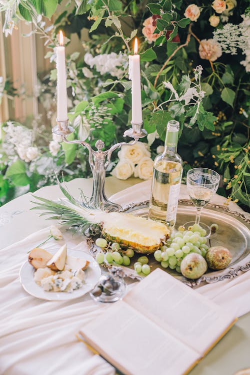 White Wine and Fruits Standing on the Table next to a Plant 