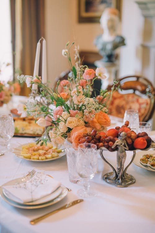 Elegant Table Setting with Fruit and Snacks and Flowers in a Vase