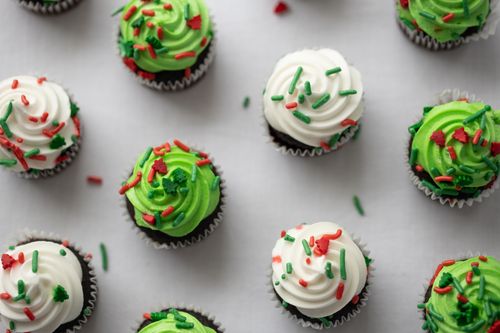 Free Delicious cupcakes with green and white icing, decorated with festive red and green sprinkles on white background. Stock Photo