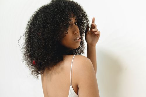 Free Stylish back view portrait of an adult woman with curly hair, in a white studio setting. Stock Photo