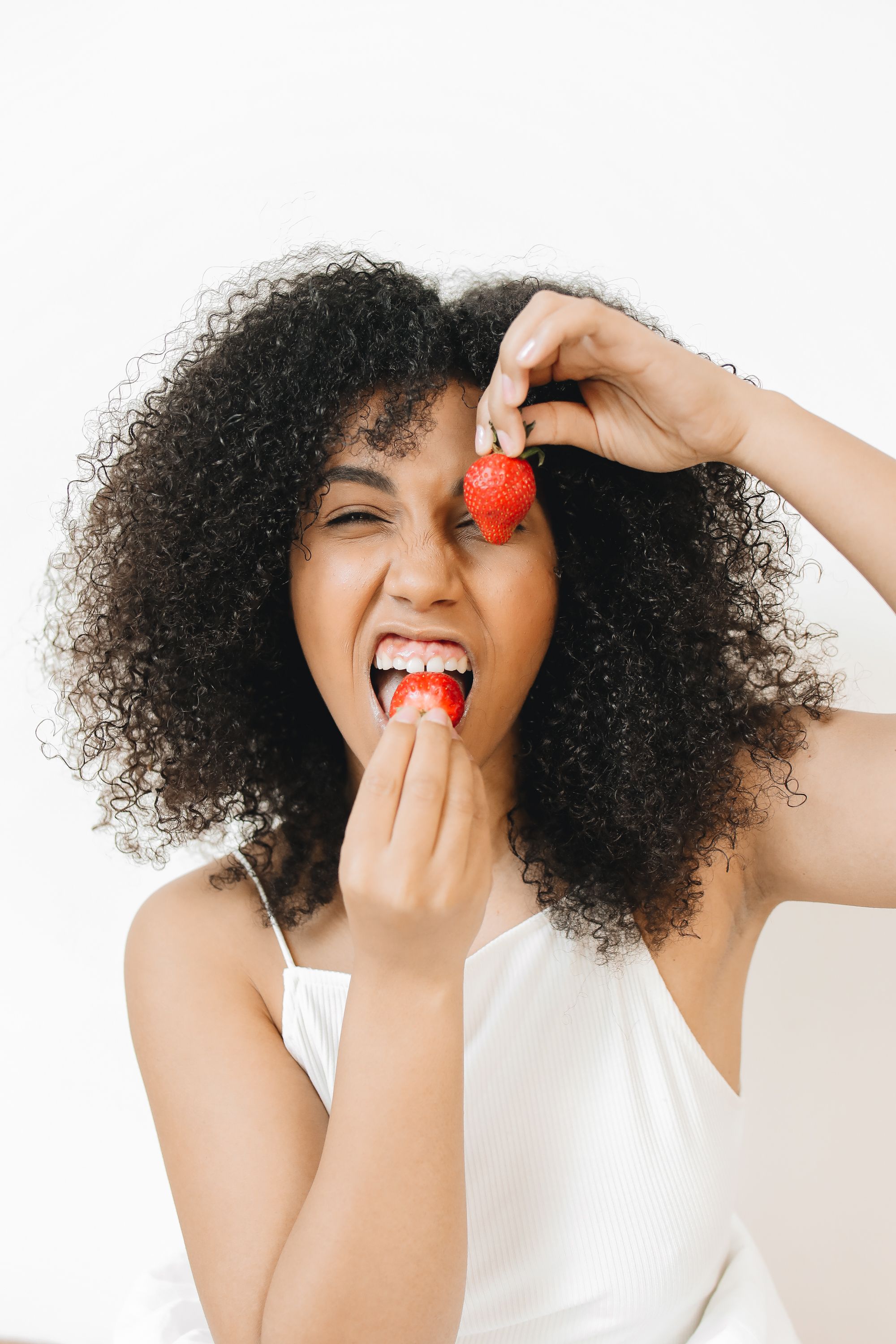 A cheerful woman eats fresh strawberries with delight. Vibrant and healthy moment captured.