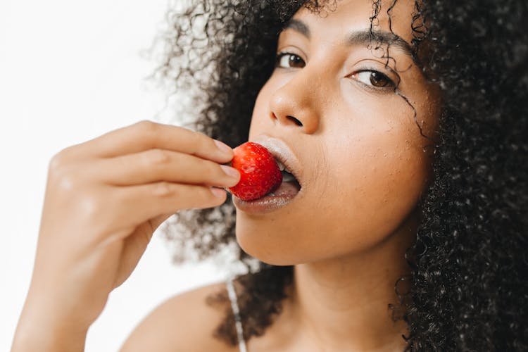 A Woman Biting A Strawberry 