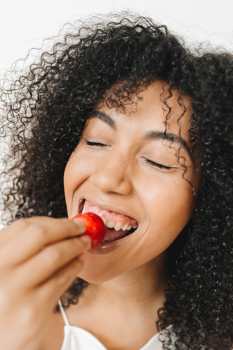 A Woman Biting A Strawberry 