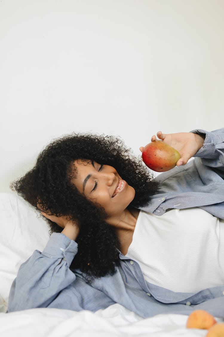 A Woman In Denim Jacket Holding An Apple