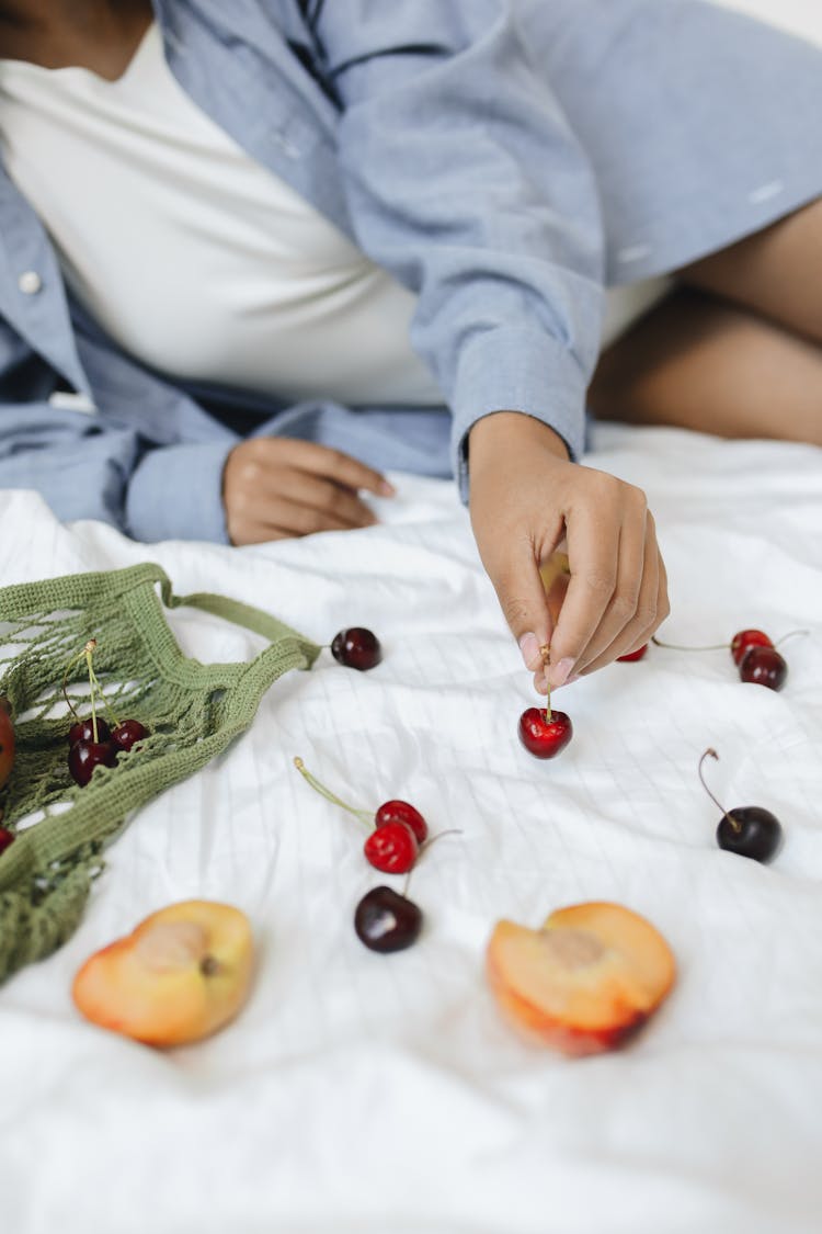 Person Sitting On Bed With Fruits