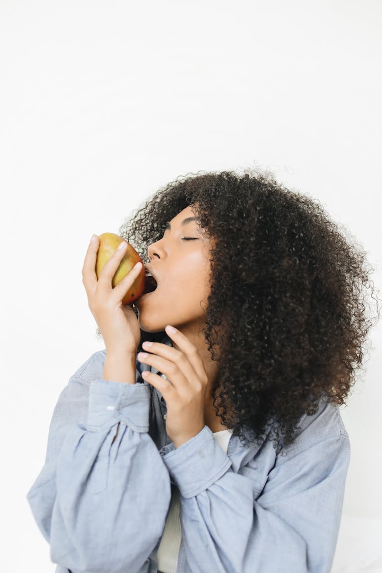 A Woman Biting A Mango