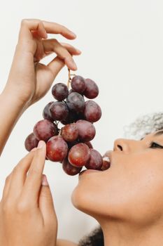 Close-up of a woman savoring fresh grapes, highlighting healthy eating.