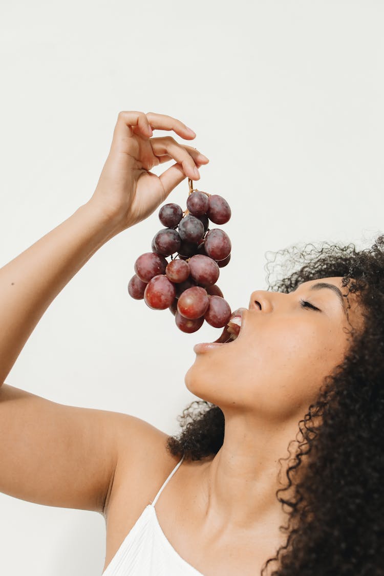 Woman In White Tank Top Eating Grapes