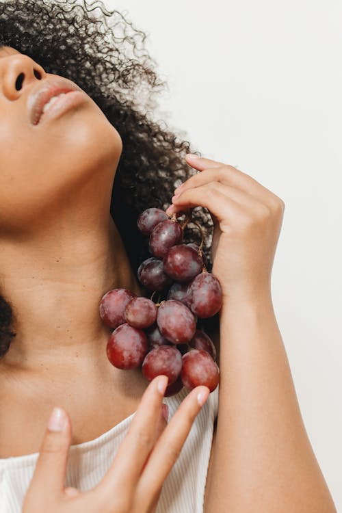 Free A Woman Holding a Bunch of Grapes Against her Neck Stock Photo