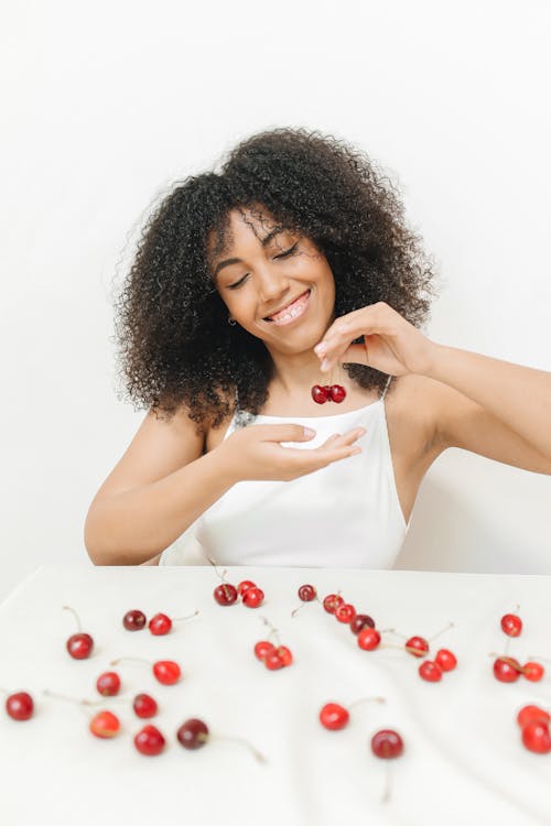 A Woman Smiling While Holding Cherries