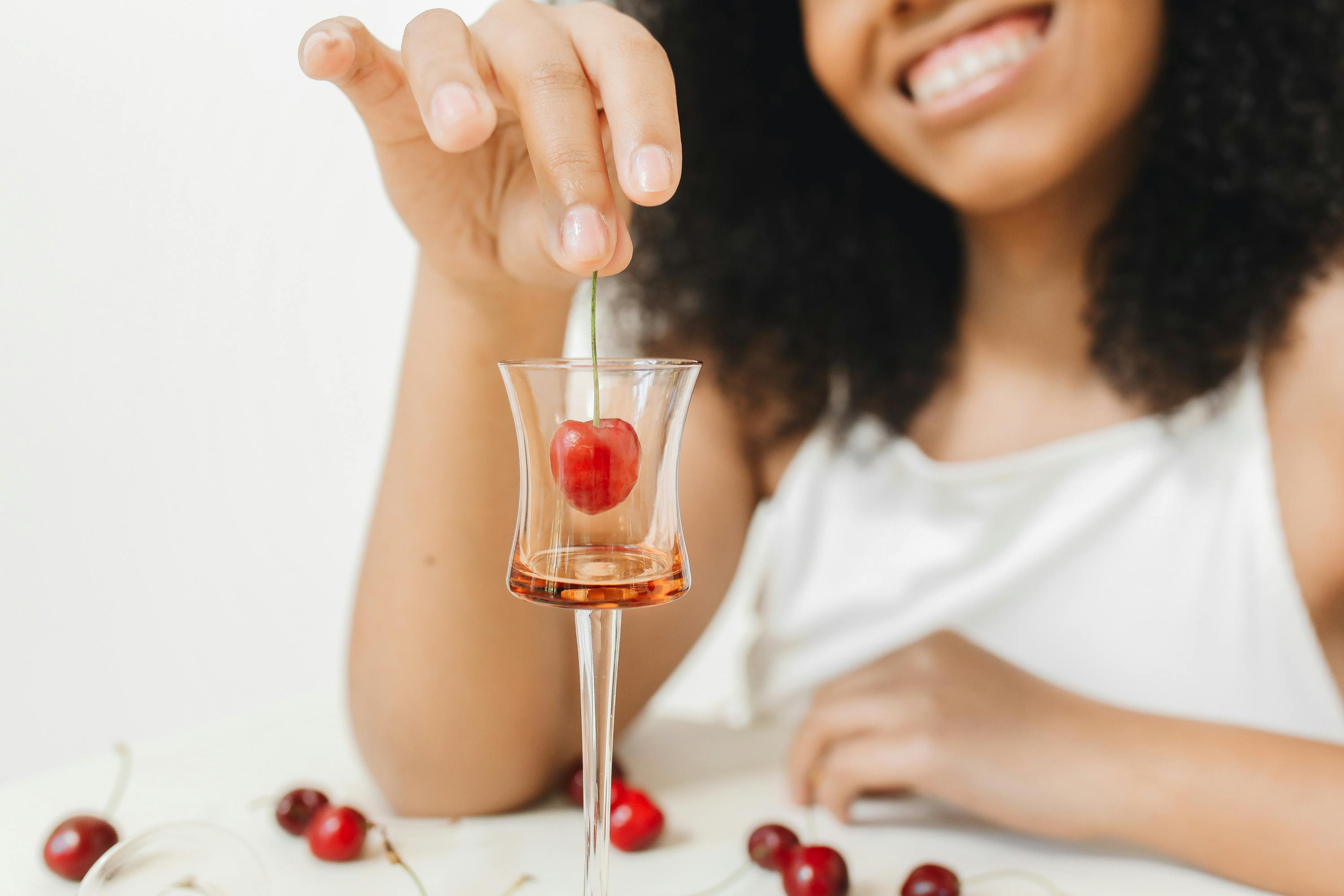 woman in white tank top putting cherry in the glass