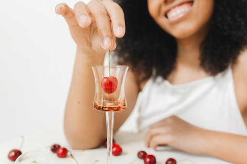 Woman in White Tank Top Putting Cherry in the Glass