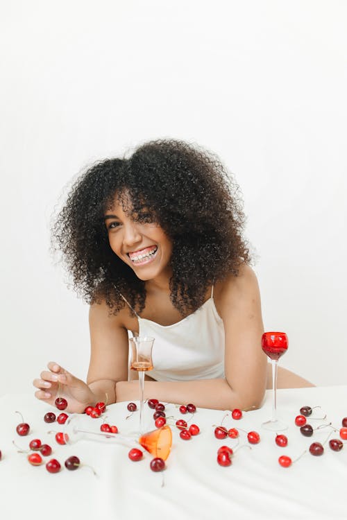 Woman Sitting at A Table with Cherries and Wine Smiling 