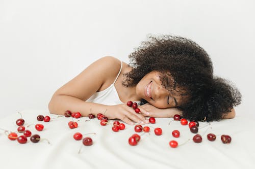 Woman Lying on White Cloth Among Cherries