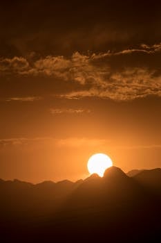 Dramatic golden sunset over Monterrey's mountains with silhouetted peaks against the sky.