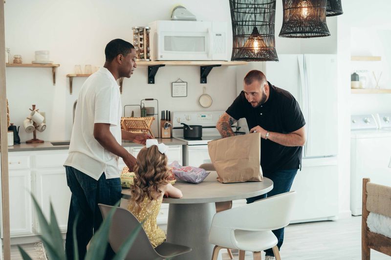 A family unpacking groceries together in a contemporary kitchen setting.