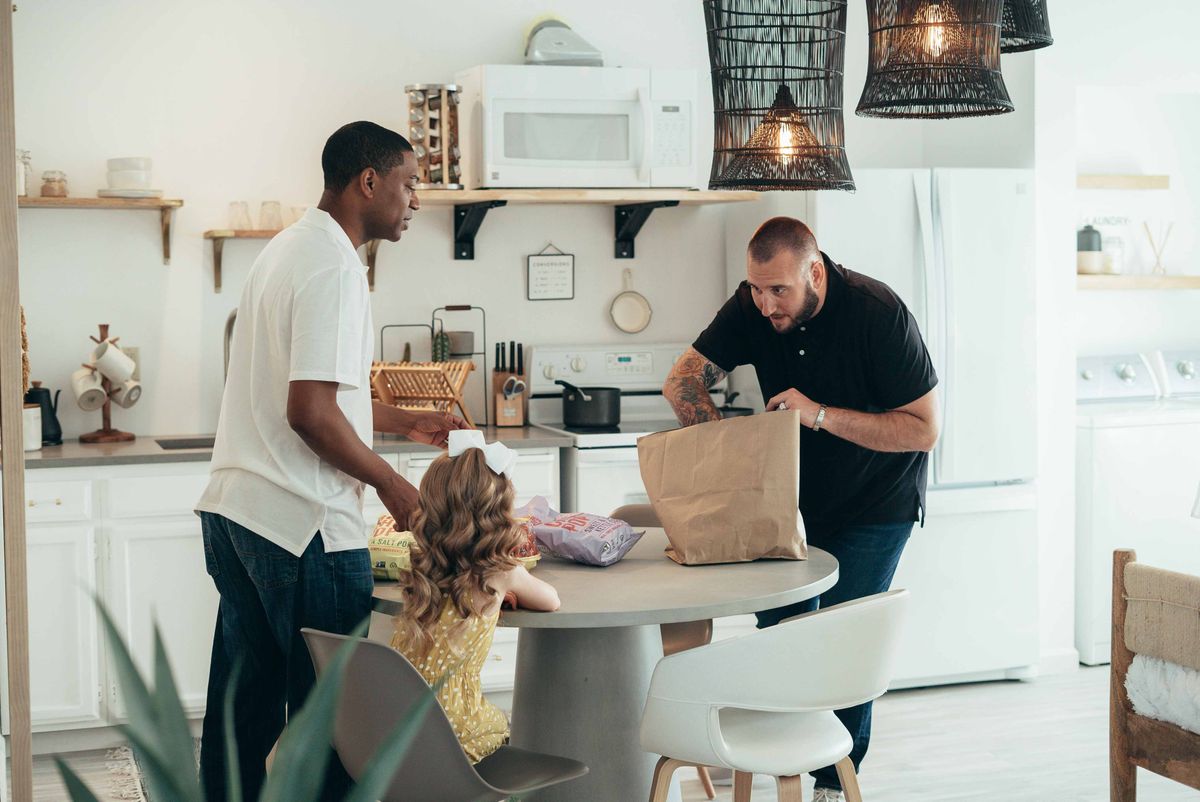A family unpacking groceries together at a kitchen table
