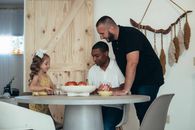 A family moment around the table with two men and a girl enjoying snacks indoors.