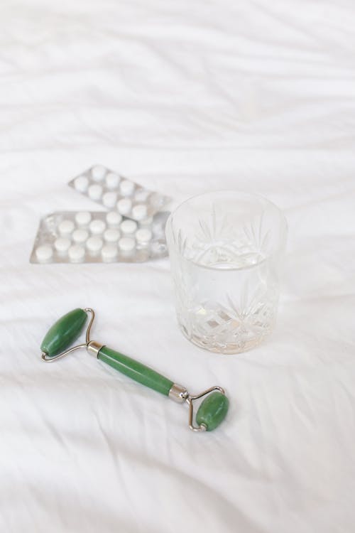 Photograph of a Glass Beside a Jade Roller