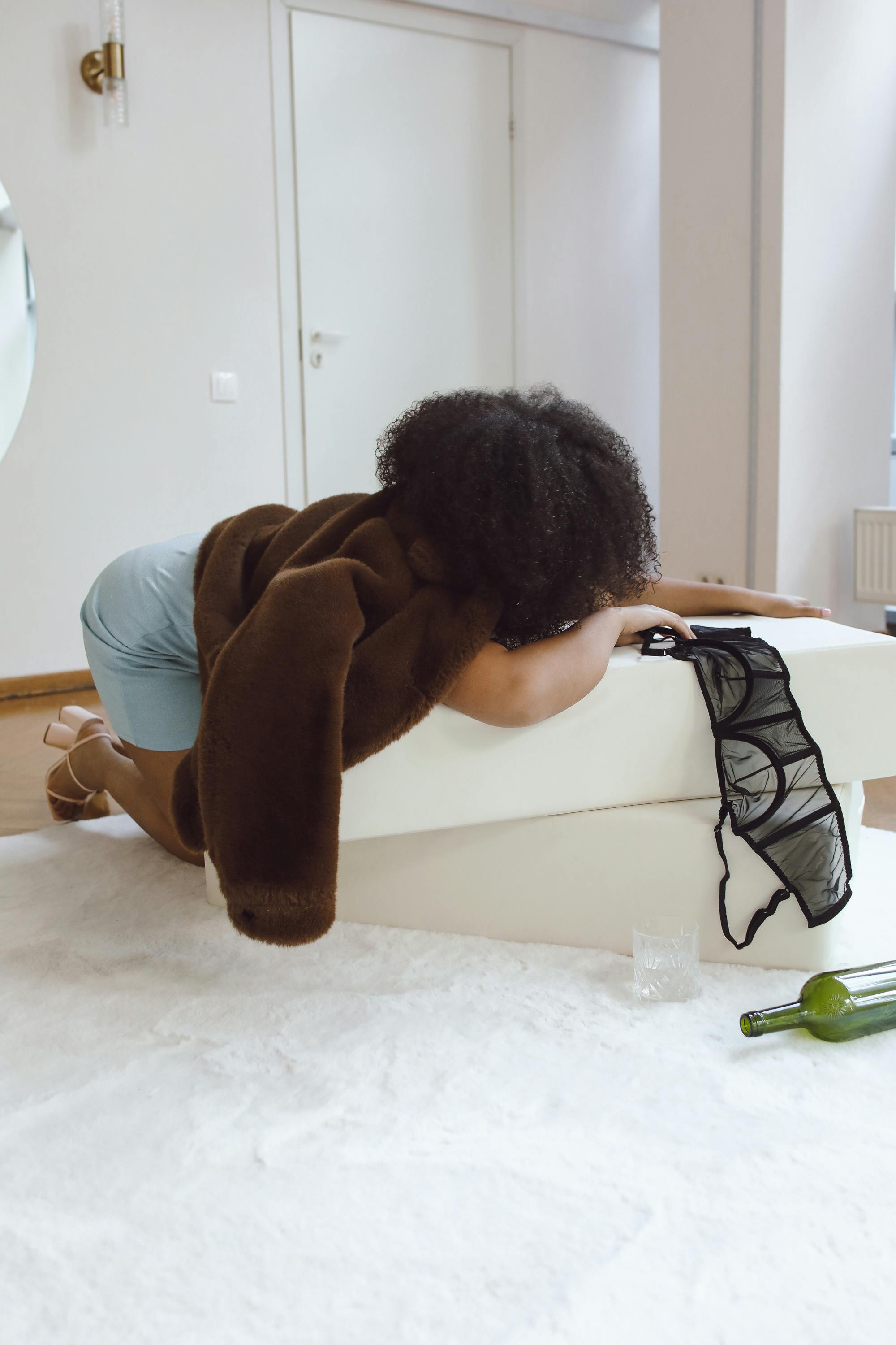 A woman in a relaxed pose on a sofa with a glass and wine bottle nearby.