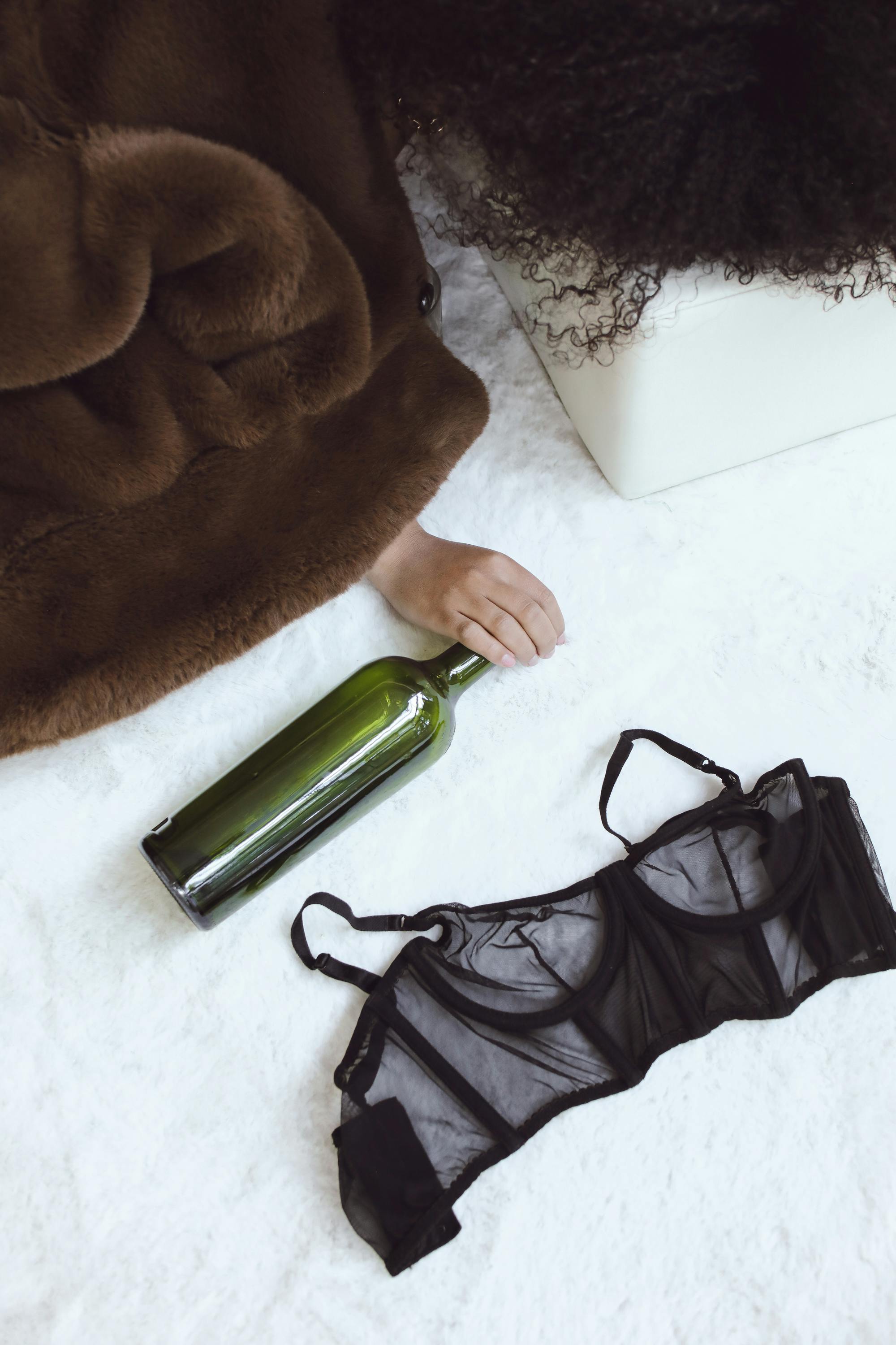 A fur coat, empty wine bottle, and lingerie hint at a carefree after-party moment.