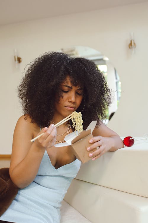 Woman Eating Takeaway Noodles with Chopsticks