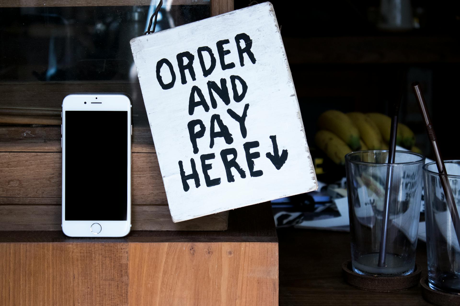 A phone next to an 'Order and Pay Here' sign in a cozy indoor setting, perfect for business use.