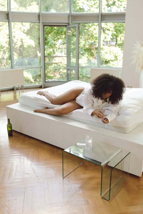 Woman in White Long Sleeve Shirt Lying on Bed