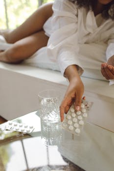 A woman in bed reaches for pills, symbolizing health or morning routine.