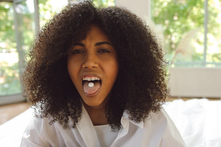 Woman With A Tablet On Her Tongue