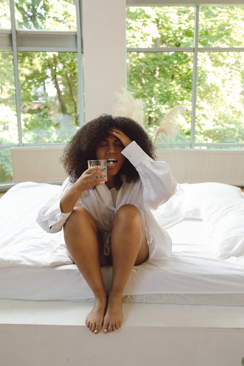 Woman in White Long Sleeve Shirt Sitting on Bed