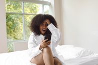 Photo of a Surprised Woman Holding Her Black Cellphone