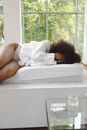 A Woman Lying in Bed Covering Her Face