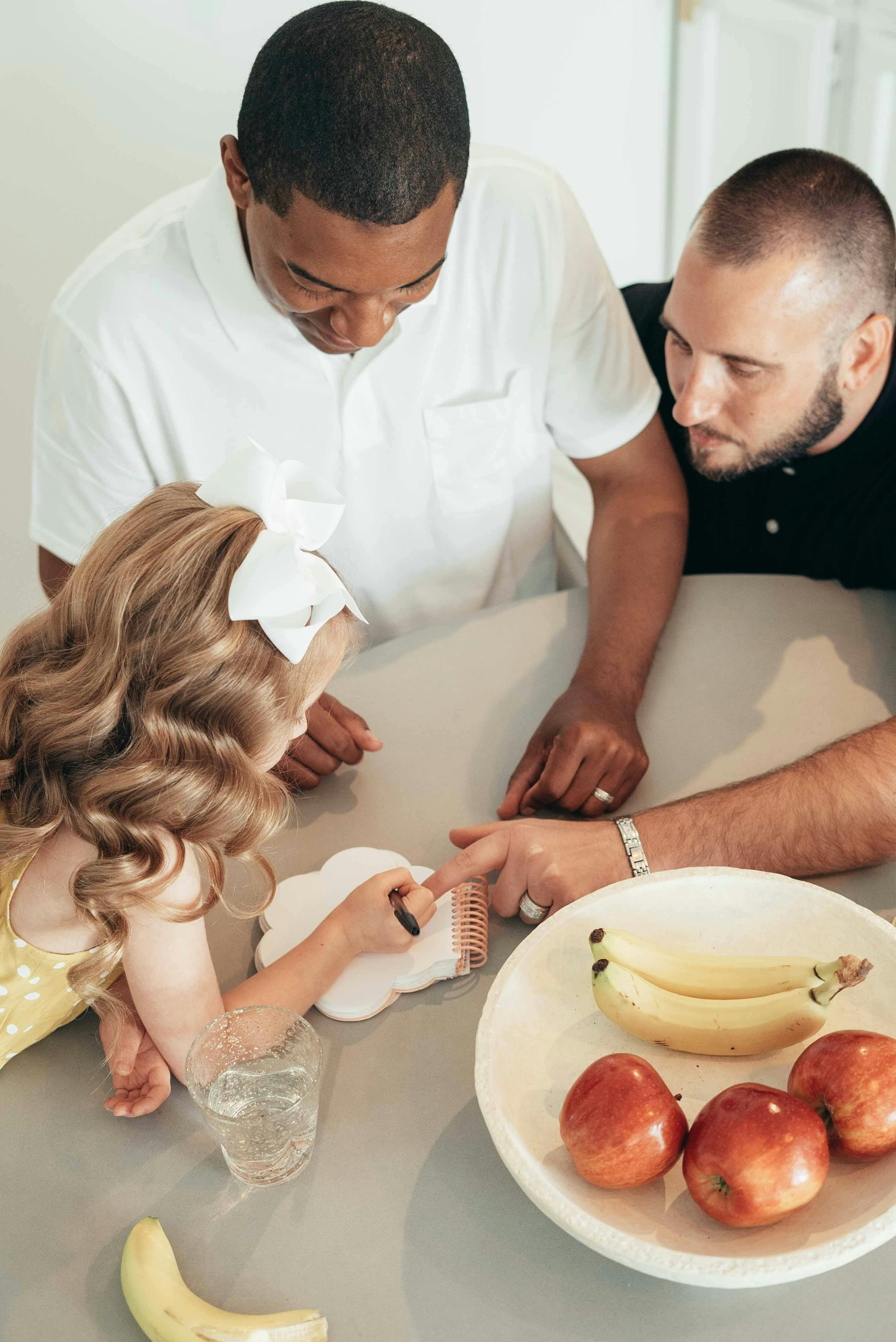 people sitting on table with fruits on ceramic bowl