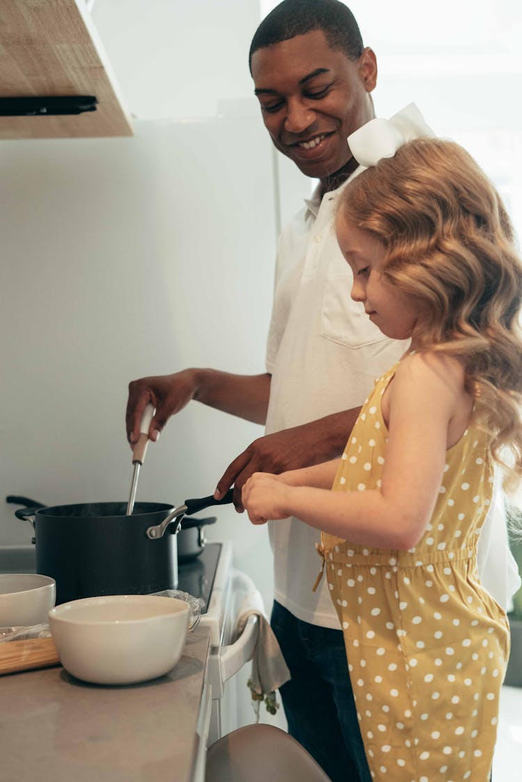 Man Cooking With Girl In Kitchen