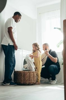 Cheerful family engaged in laundry activity in a bright, airy room with a wicker basket.